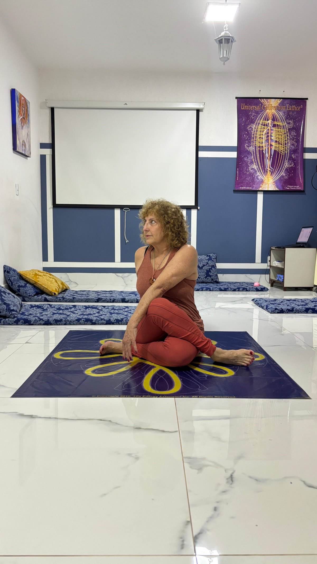 Lindalva Dias demonstrando Virasana com torção no Espaço Sol em Brasília, sobre tapete Universal Calibration Lattice